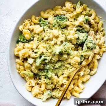 vegan mac and cheese made with cashew cheese in a bowl with a gold fork and broccoli