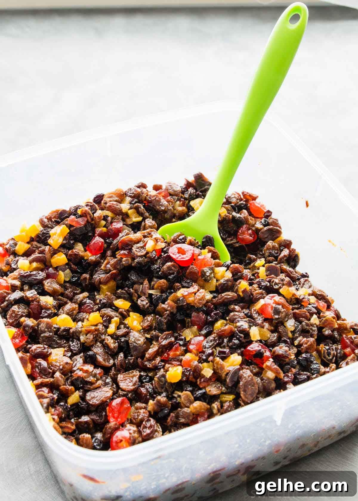 A large square plastic container of mixed dried fruits after soaking in brandy.