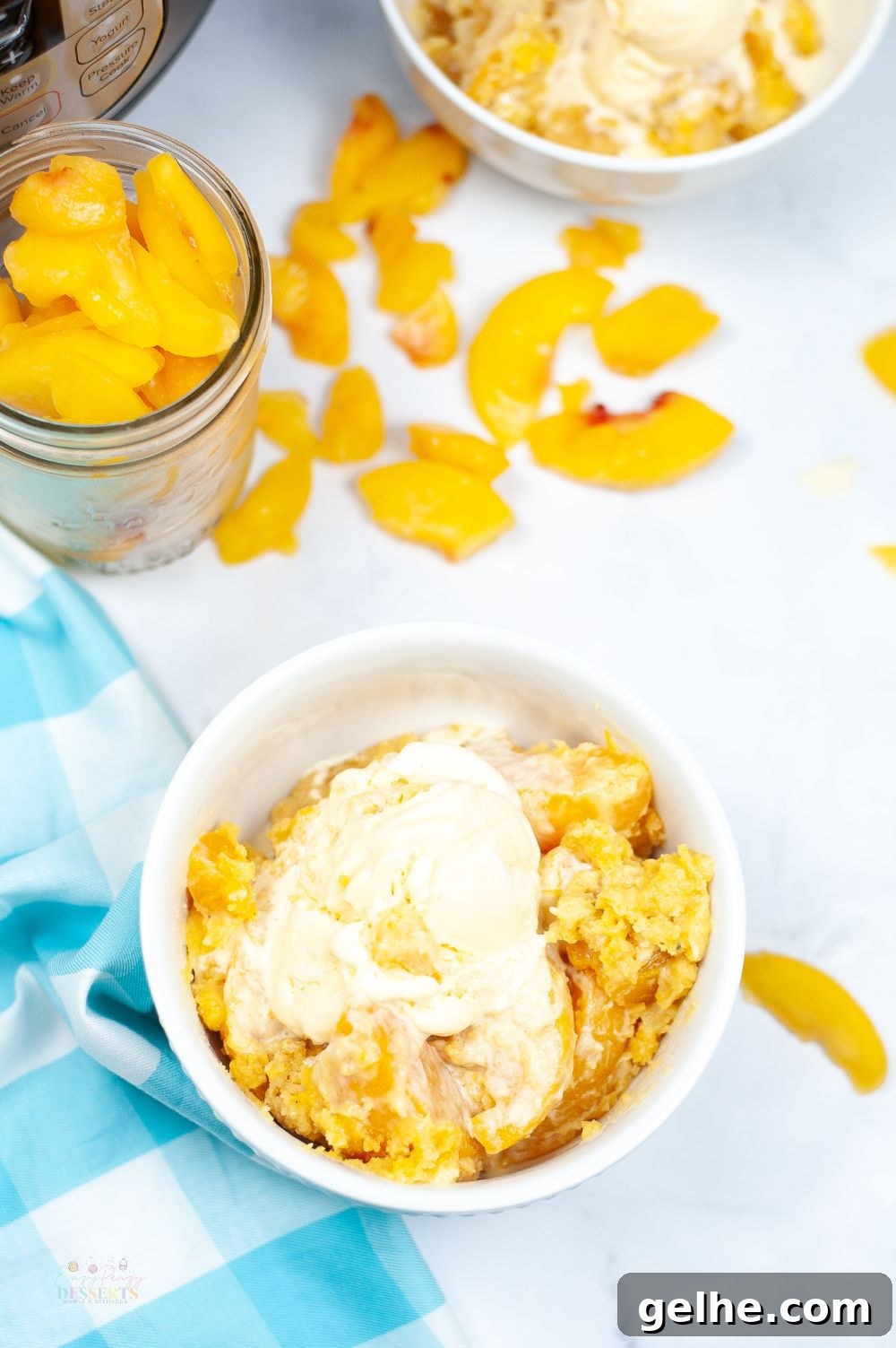 Image of instant pot peach cobbler in a white bowl, topped with vanilla ice cream