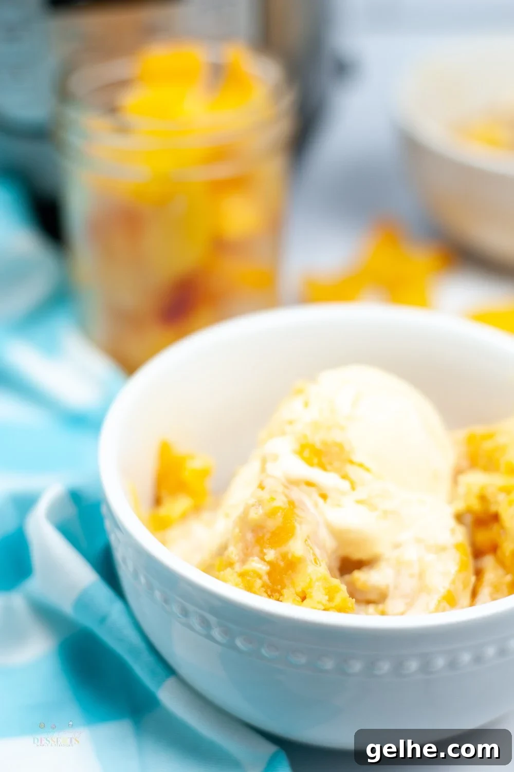 Side image of instant pot peach cobbler in a white bowl, topped with vanilla ice cream