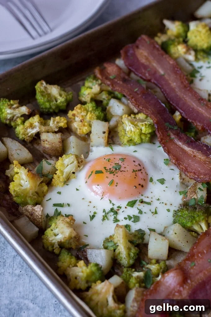 Whole30 Sheet Pan Breakfast Bake for Busy Mornings 2 zoomed in shot of a cooked egg on a sheet pan with potatoes, romanesco and bacon for this Easy Sheet Pan Breakfast dish