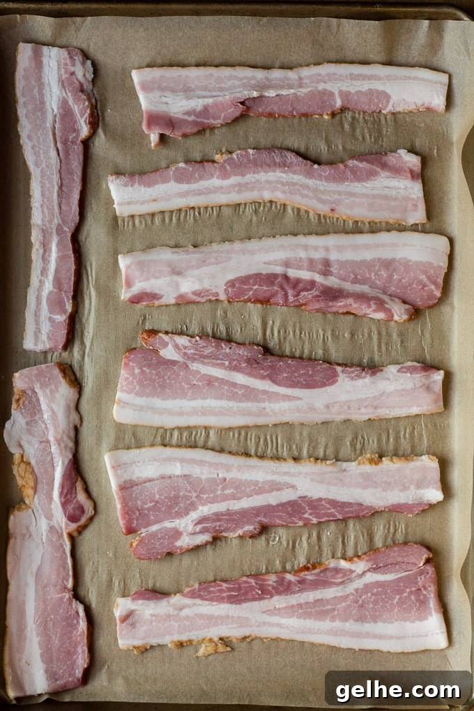 Whole30 Sheet Pan Breakfast Bake for Busy Mornings 4 top down view of 8 raw bacon slices on top of parchment paper in a sheet pan