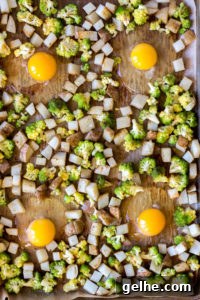 top down view of 4 eggs in wells with cubed pototoes and romanesco on a sheet pan