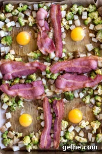 Whole30 Sheet Pan Breakfast Bake for Busy Mornings 7 top down view of eggs surround by cubed potatoes, romanesco, and strips of bacon on a sheet pan