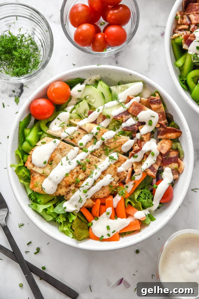 Chicken Bacon Ranch Salad Recipe: Creamy, Crunchy Weeknight Favorite 10 prepared go-to chicken bacon ranch salad in a white bowl with ranch dressing and herbs on top.