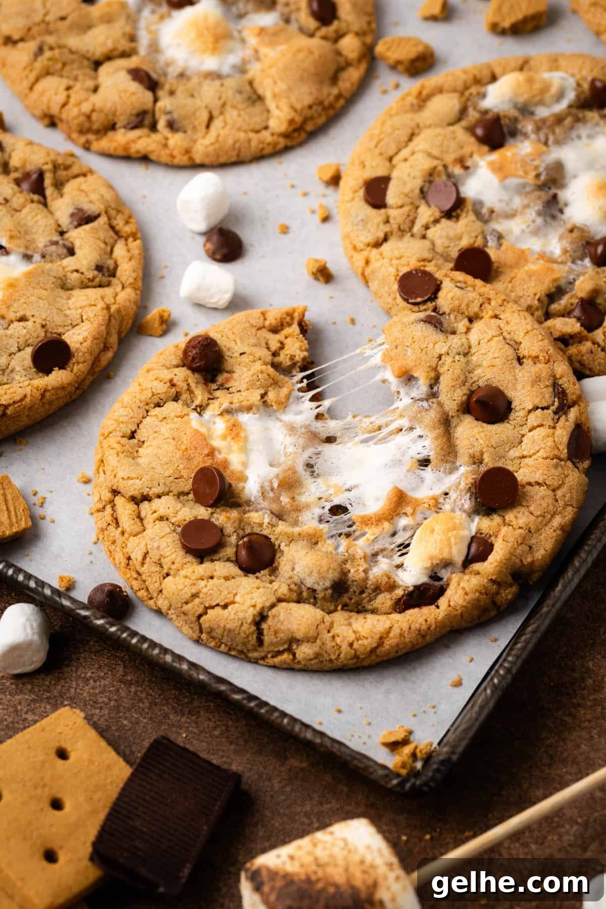 A baked s'mores chocolate chip cookie broken in half and showing the gooey marshmallow center.