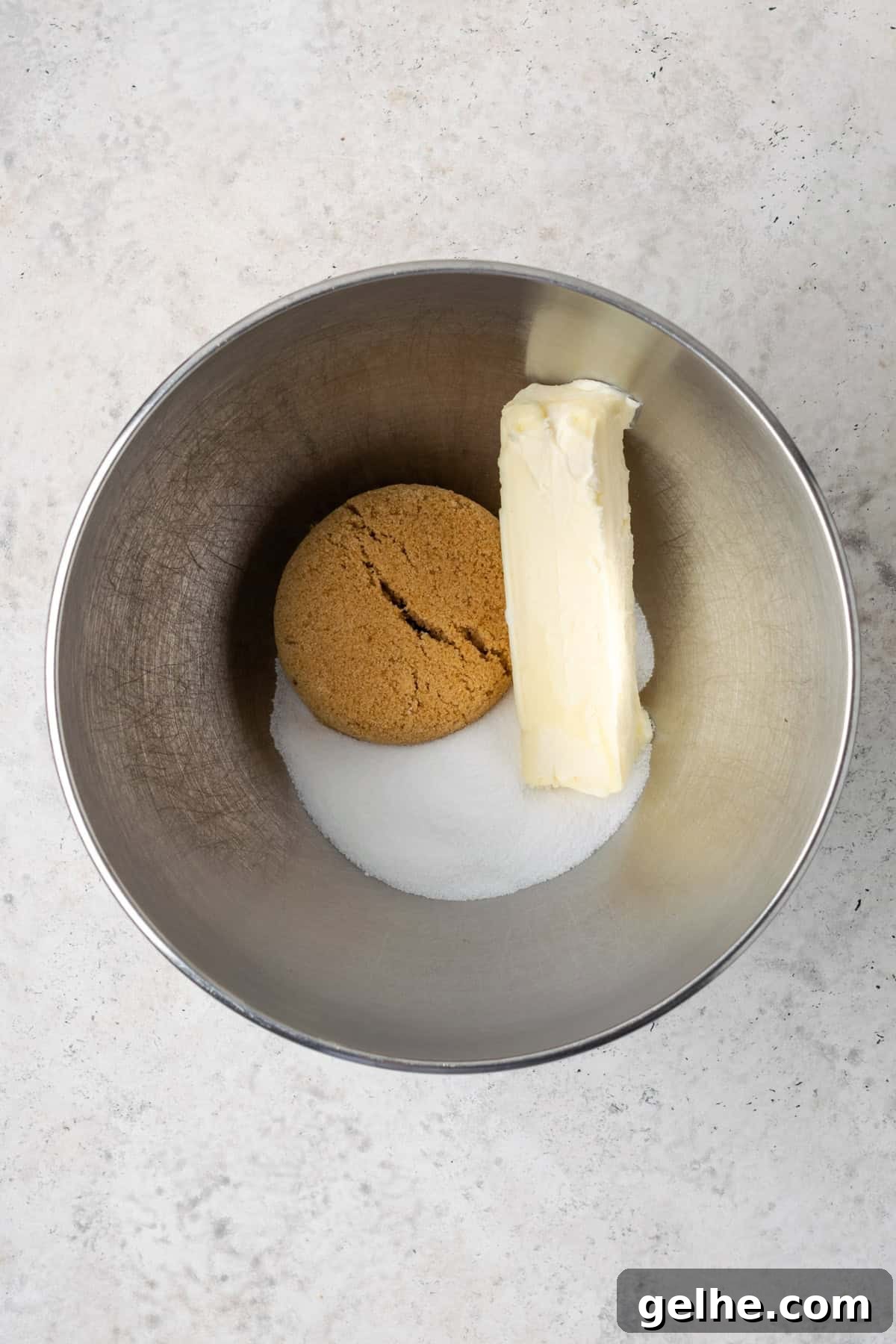 Sugar, brown sugar and butter combined in a metal mixing bowl.