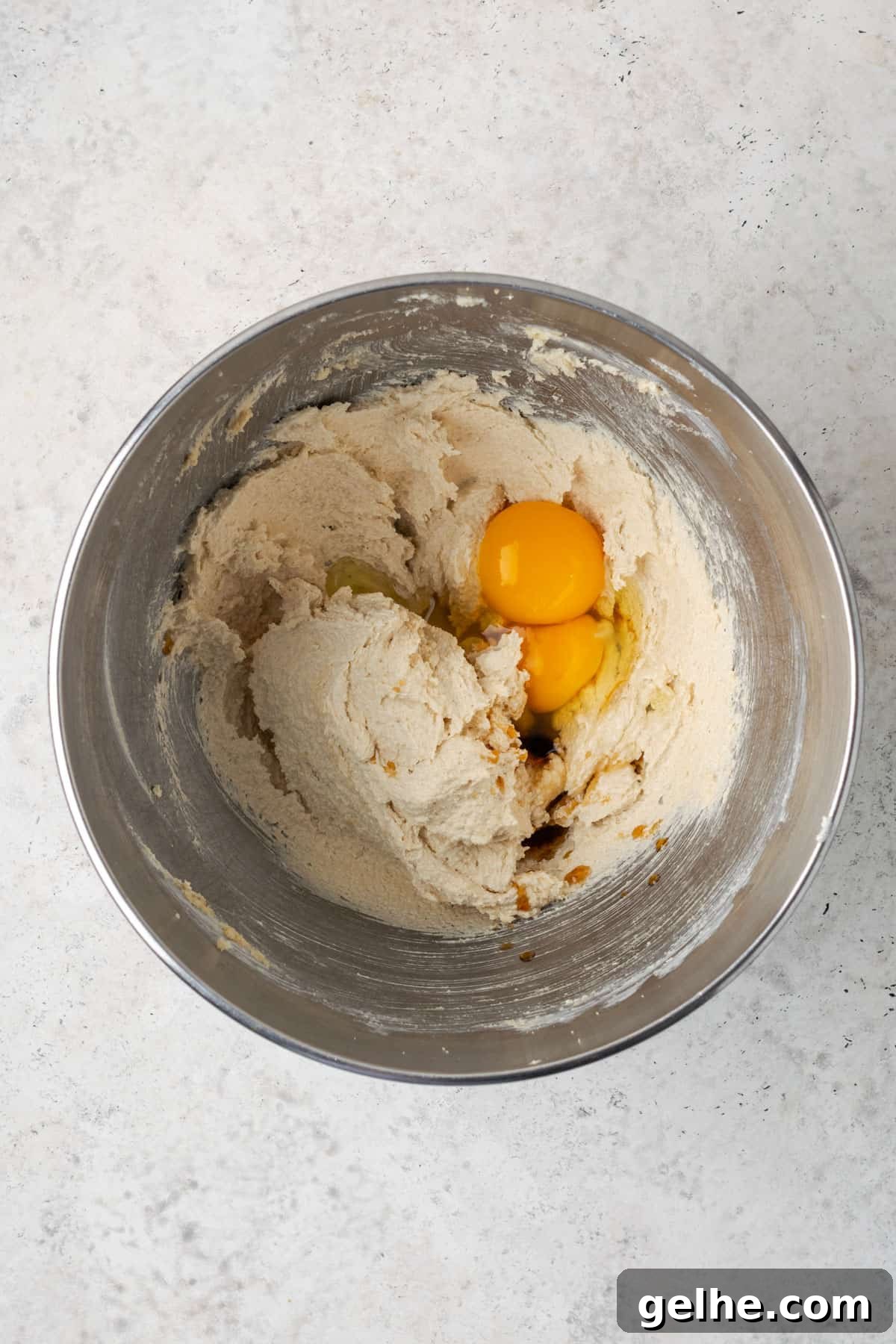 Vanilla extract, egg and egg yolk added to the creamed butter and sugar in a metal mixing bowl. 