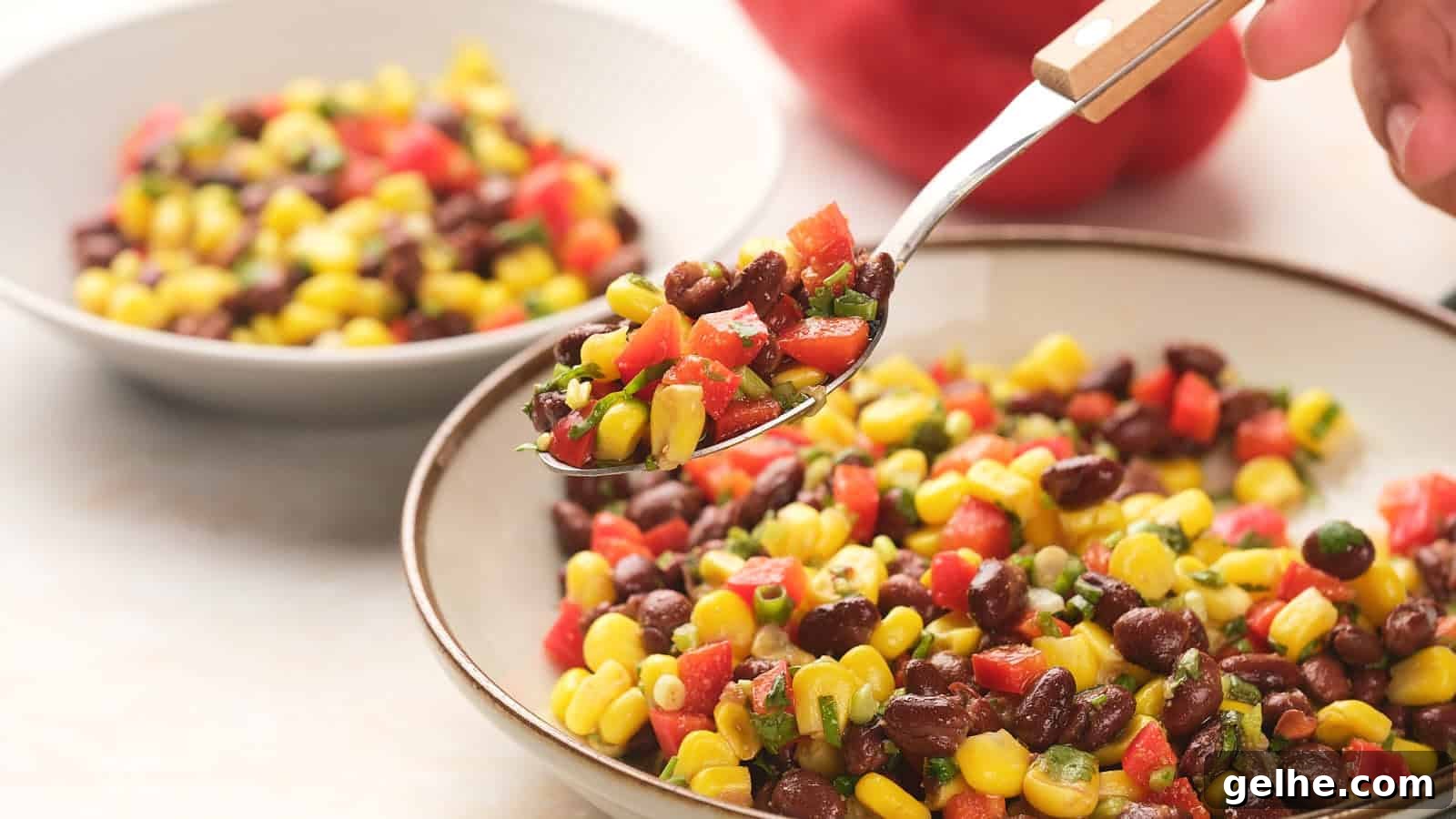 21 Labor Day Picnic Recipes for a Crowd: Ultimate Menu Ideas 5 A bowl of black bean salad sits on a table with a spoon and a second small bowl in the background.