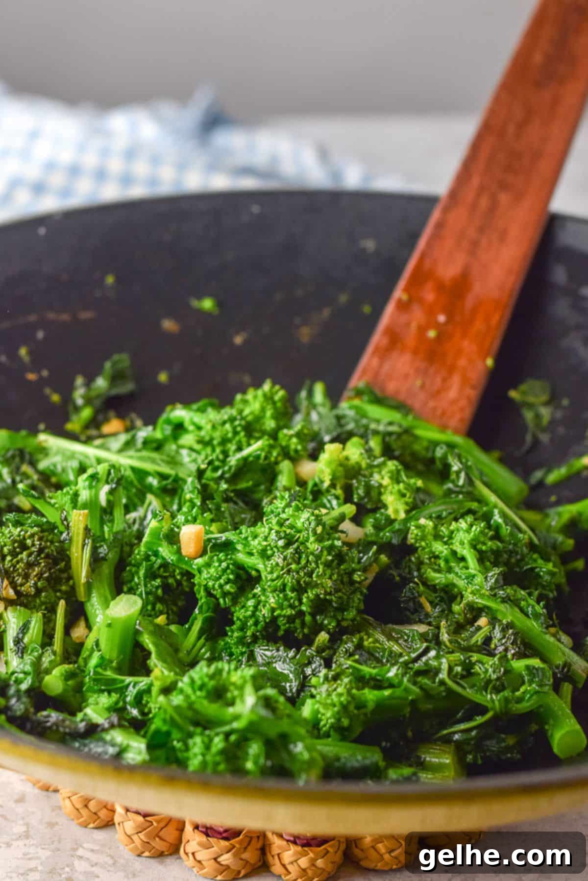 A yellow wok filled with cooked broccoli rabe