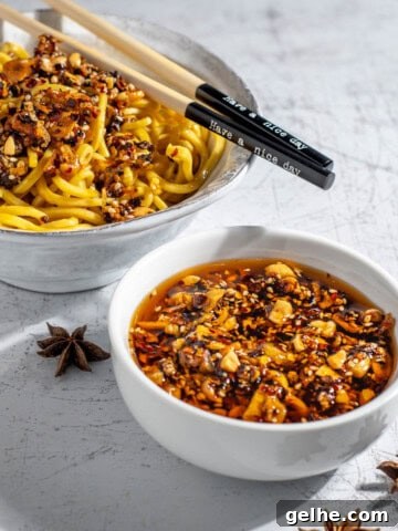A bowl of crispy chilli oil alongside a bowl of egg noodles.