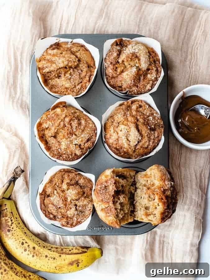 Overhead shot of 6 banana muffins in tin with one cut open to see dulce de leche swirled inside