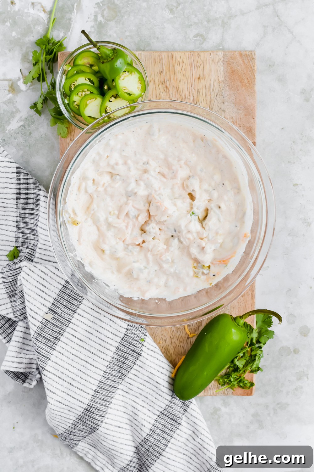 Baked Cheddar Jalapeño Dip with Crispy Panko Topping 4 ingredients for cheddar jalapeño dip mixed in glass bowl on wood cutting board.