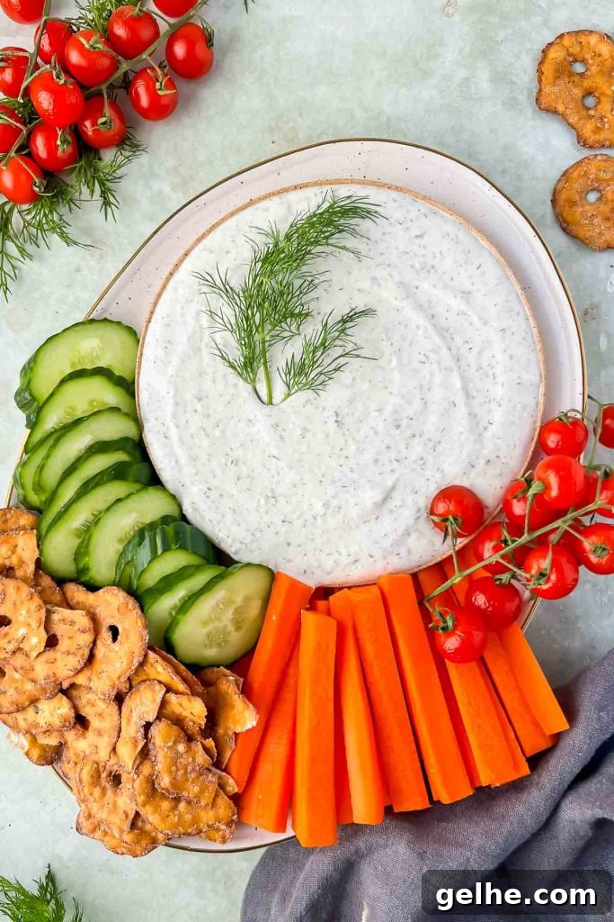 Baked Cheddar Jalapeño Dip with Crispy Panko Topping 9 cottage cheese ranch dip with fresh dill as garnish on plate with cucumbers, carrots and pretzels.