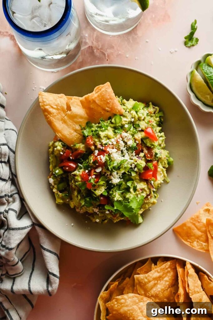 Baked Cheddar Jalapeño Dip with Crispy Panko Topping 10 chip dipped into avocado crack dip in ceramic serving dish topped with cilantro and feta cheese garnish.
