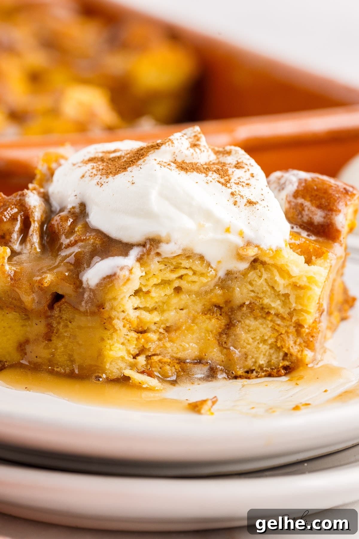 Slice of Pumpkin Bread Pudding on a plate with whipped cream on top.