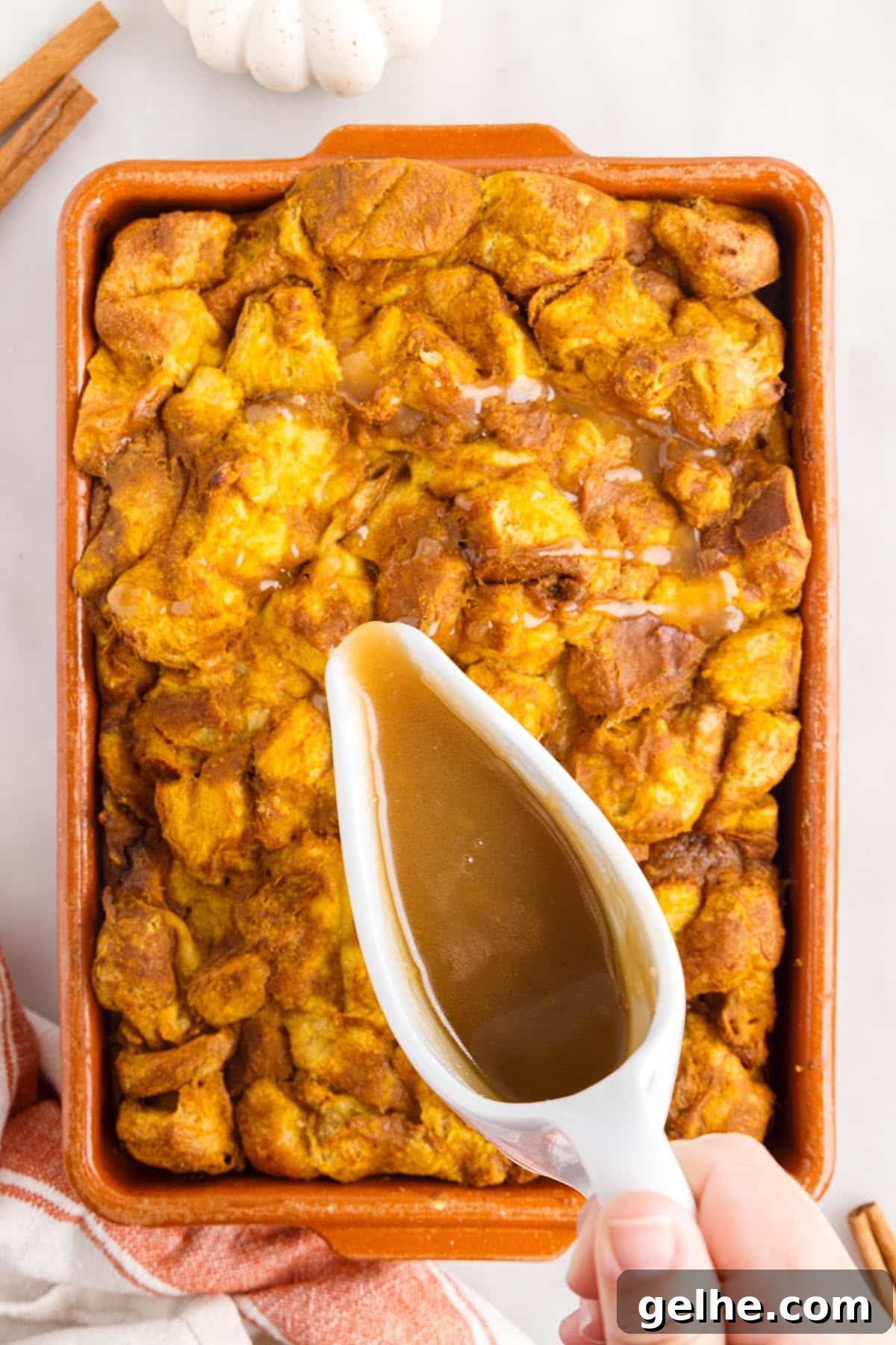 Drizzling the caramel sauce over the bread pudding.