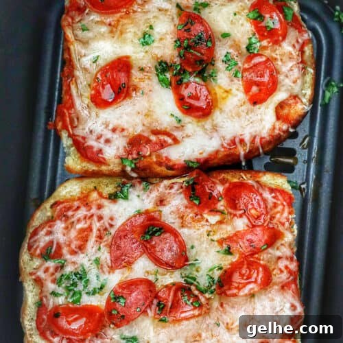 two half loaves of french bread pizza in an air fryer basket.