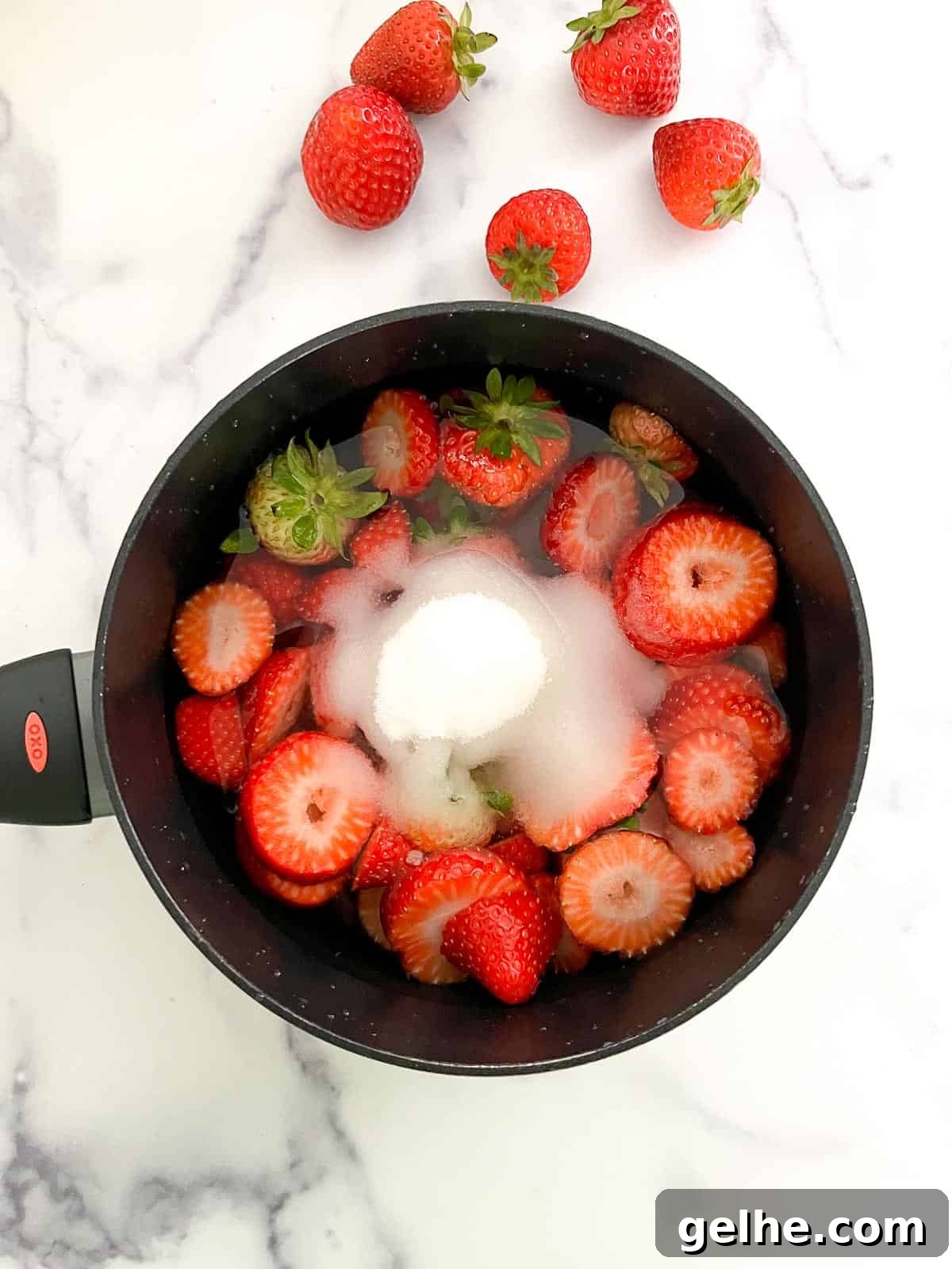 Strawberries and sugar in a saucepan with water.