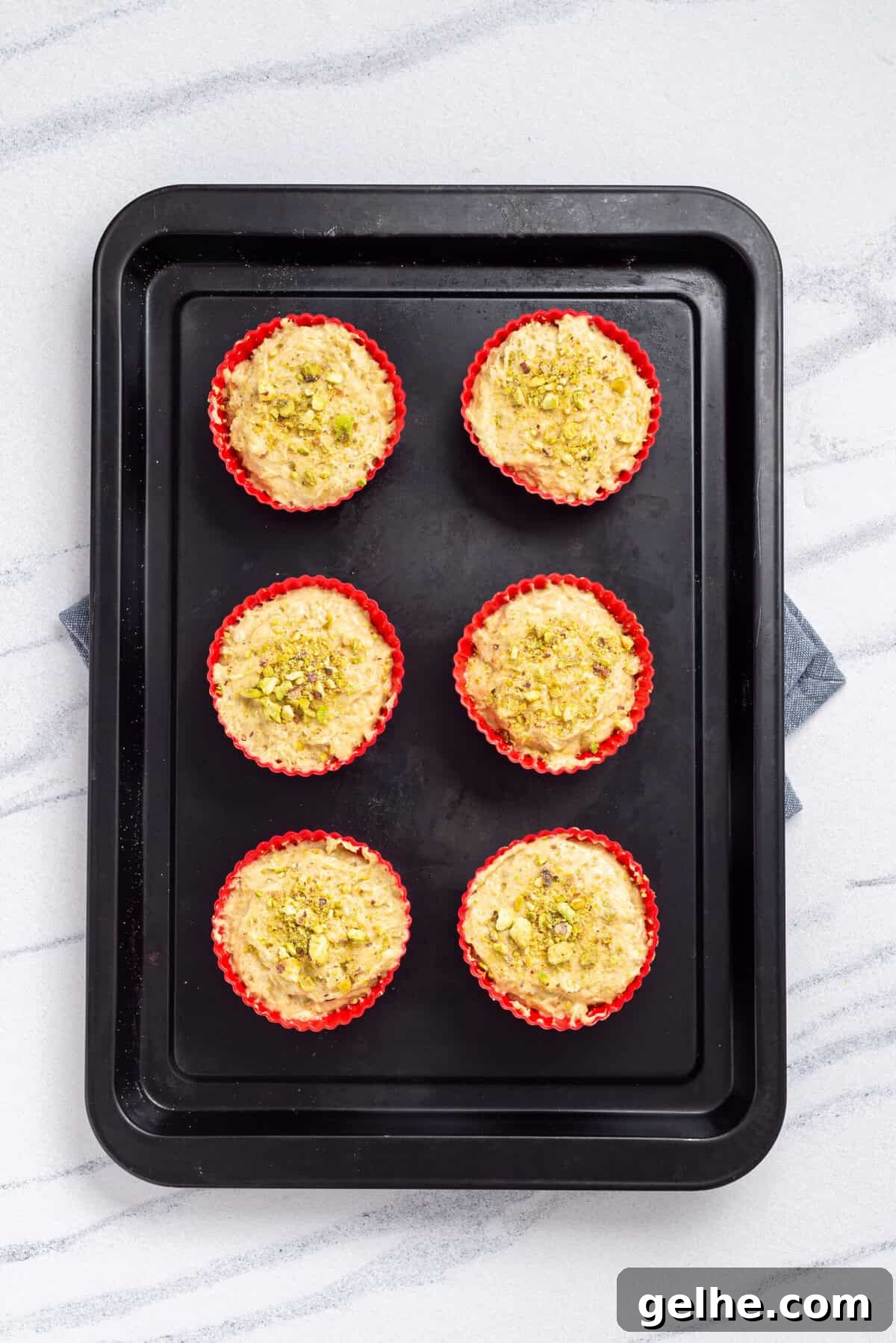 Homemade Pistachio Muffins Without Pudding Mix 10 An overhead image of uncooked pistachio muffins on a baking sheet.