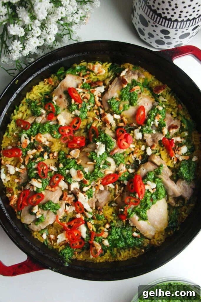 Pesto topped golden chicke and rice in a large pot.