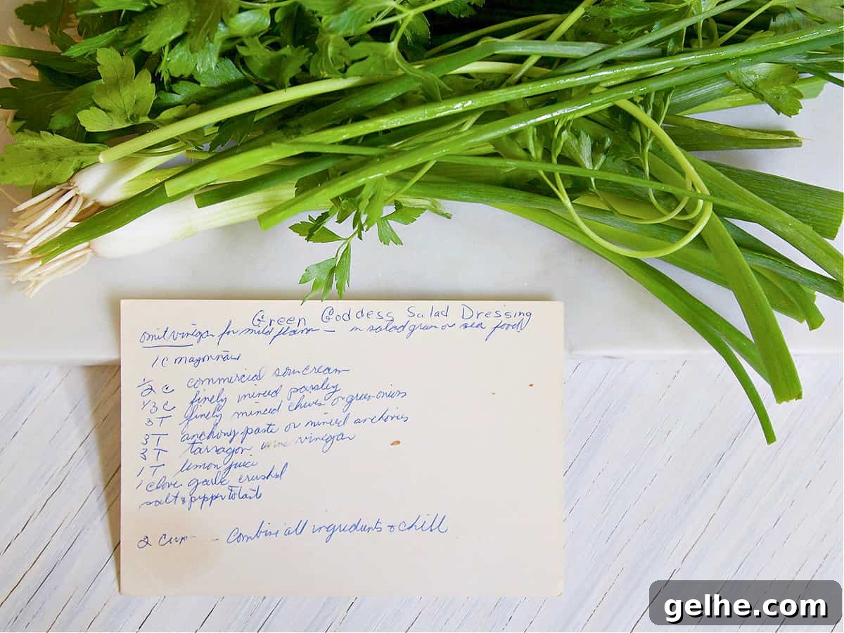A bunch of green onions and a recipe card for green goddess salad dressing handwritten.