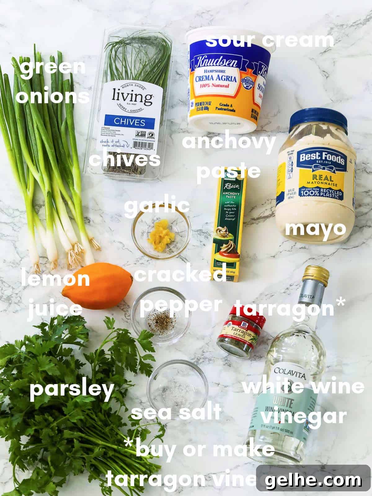 A white table with ingredients to make green goddess dressing all labeled.