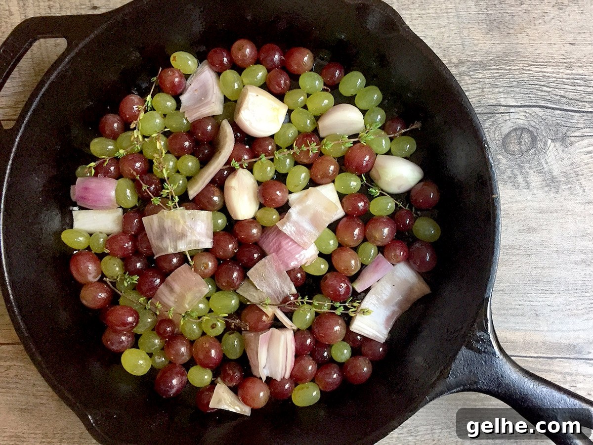 Uncooked green and red grapes in a cast iron pan with shallots.