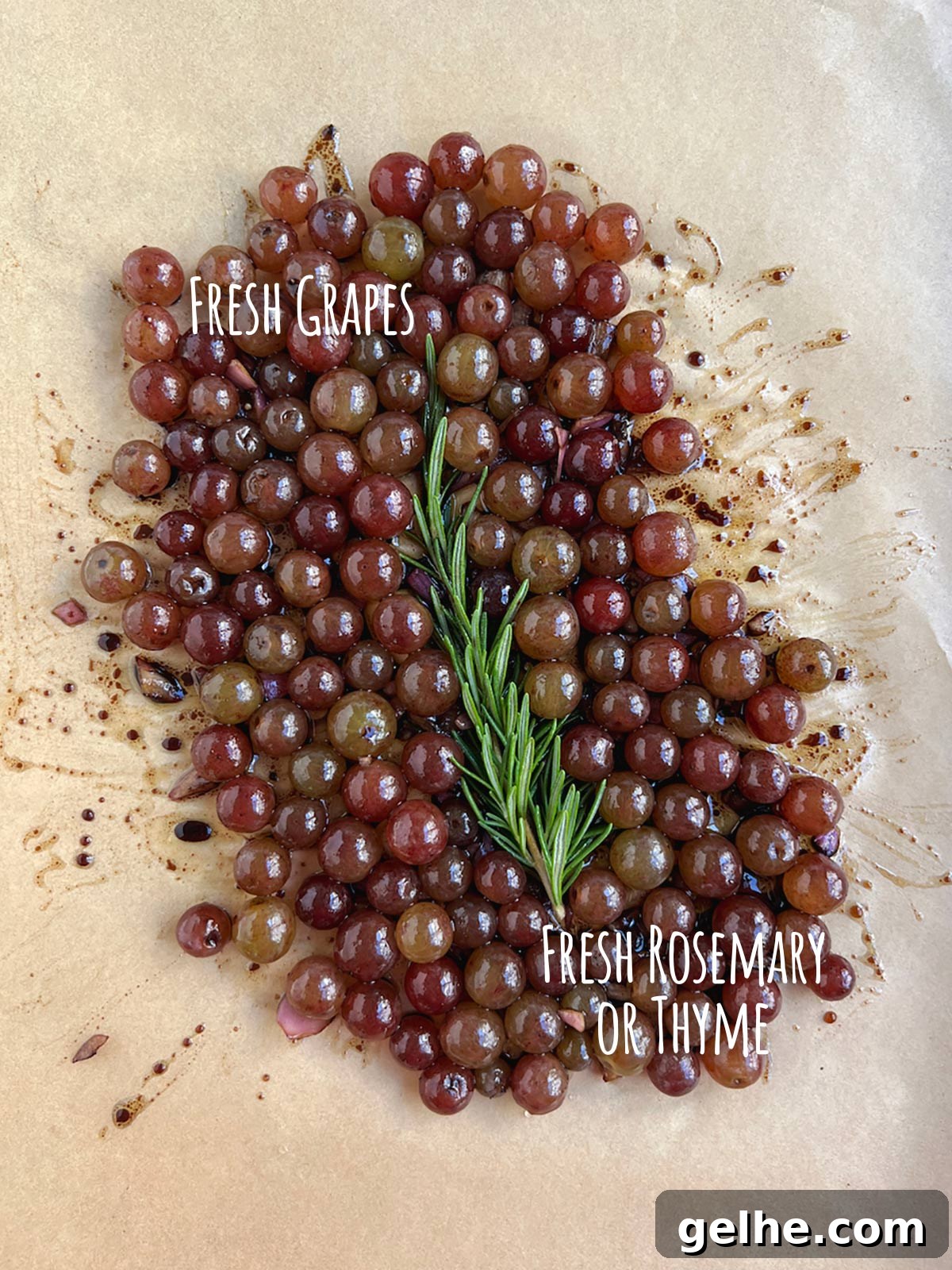 Ingredient shot for baked grapes showing fresh grapes and fresh rosemary on parchment paper.