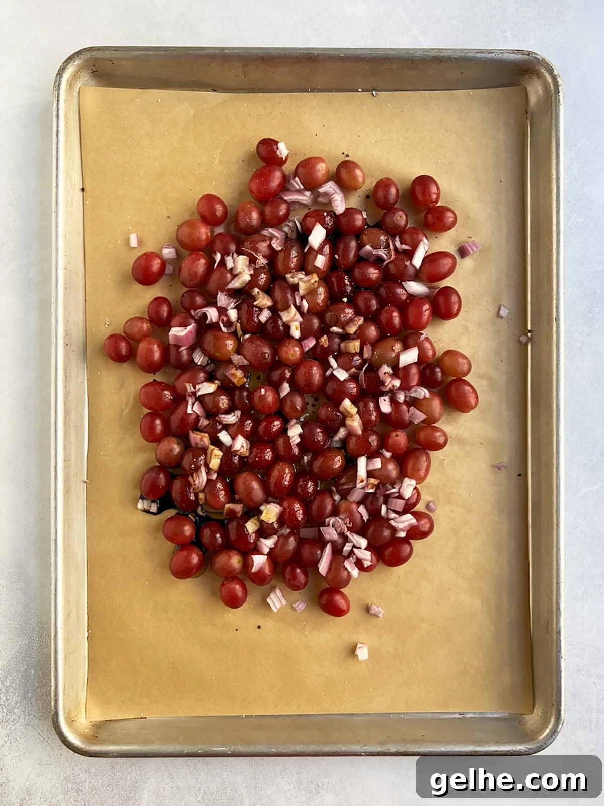 Uncooked grapes on baking tray with liquid poured over.