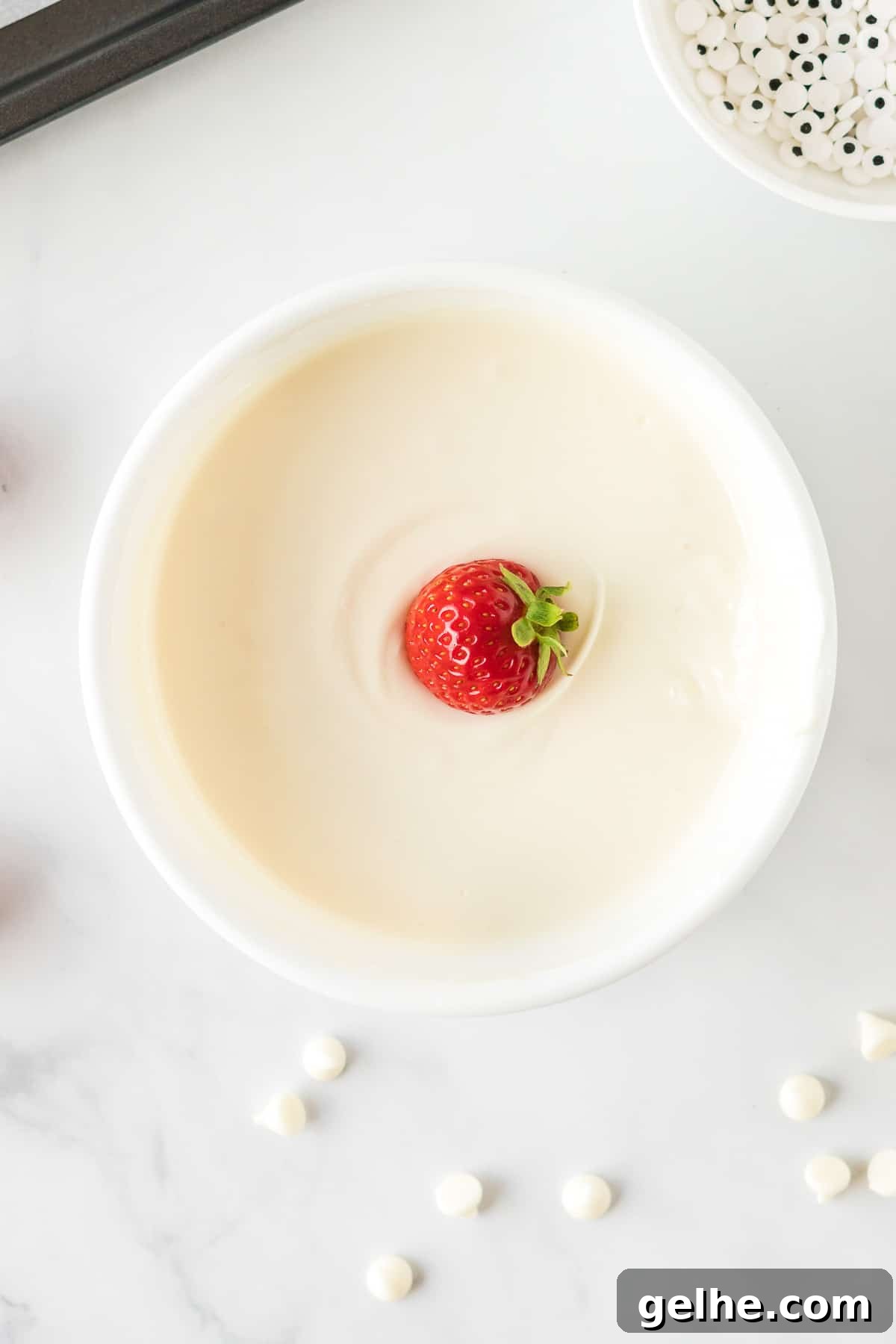 dipping a strawberry into melted white chocolate