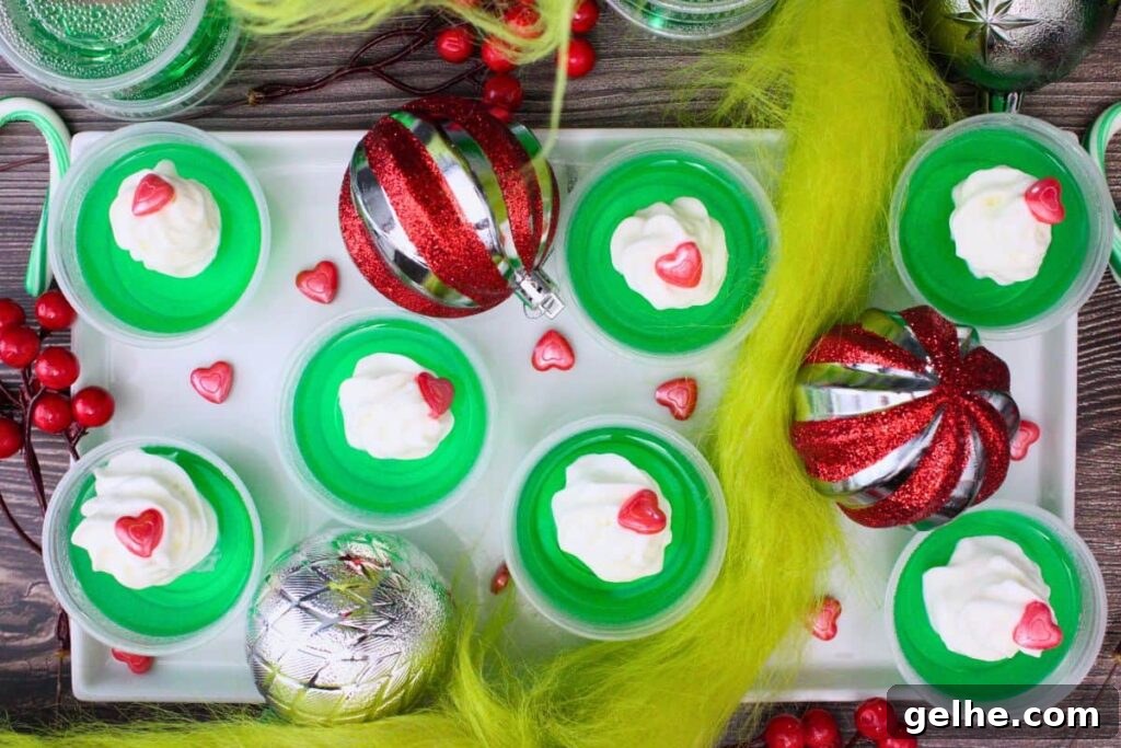 overhead view of grinch jello shots on a plate with christmas decorations and grinch garland