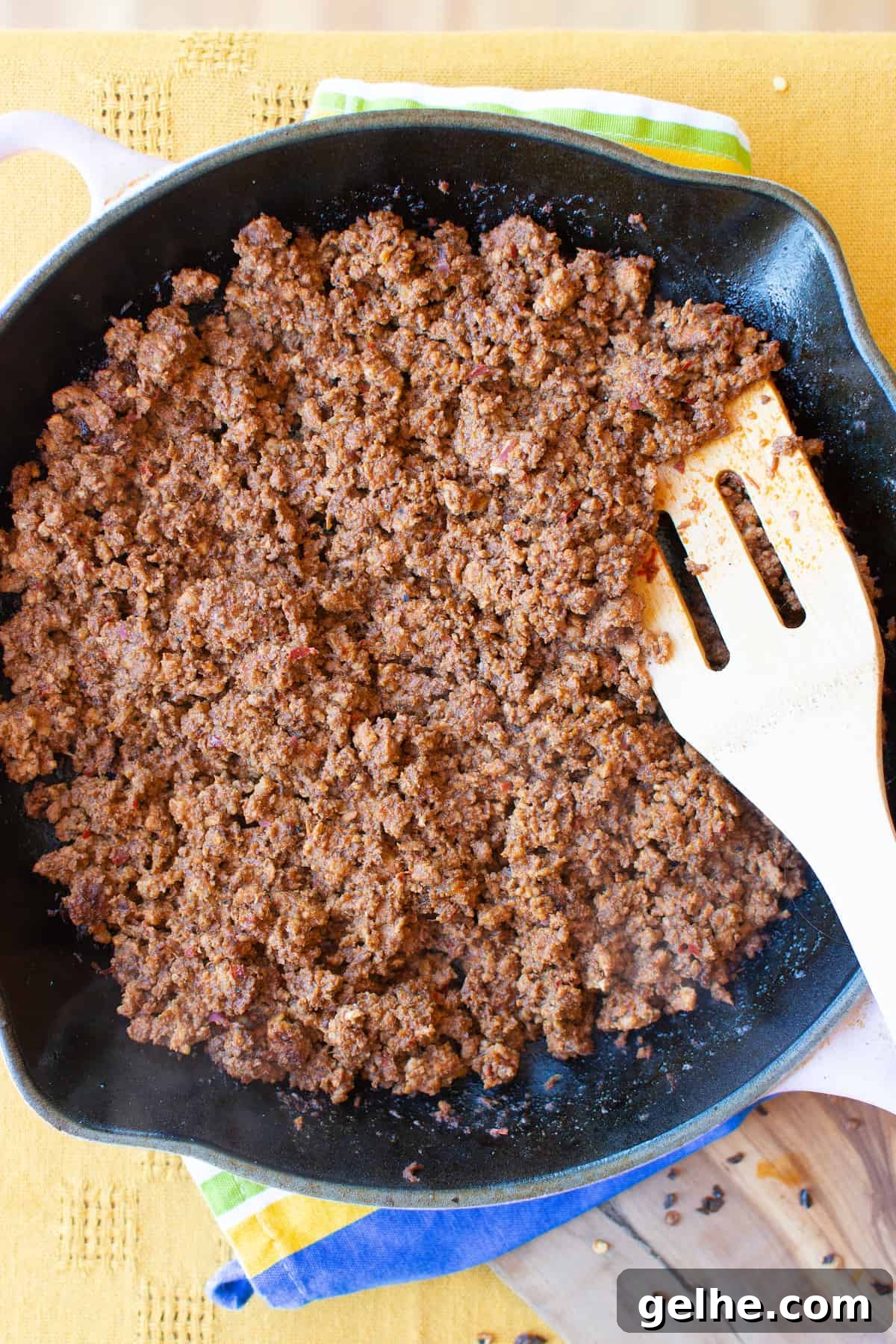 Overhead image of Mexican chorizo cooking in a skillet with a wooden spoon in one side of the pan.