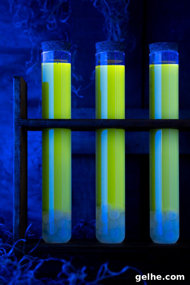 Blacklight Swamp Shot Recipe: Glow-In-The-Dark Party Drink 3 close up of black light swamp water shots glowing in a test tube rack