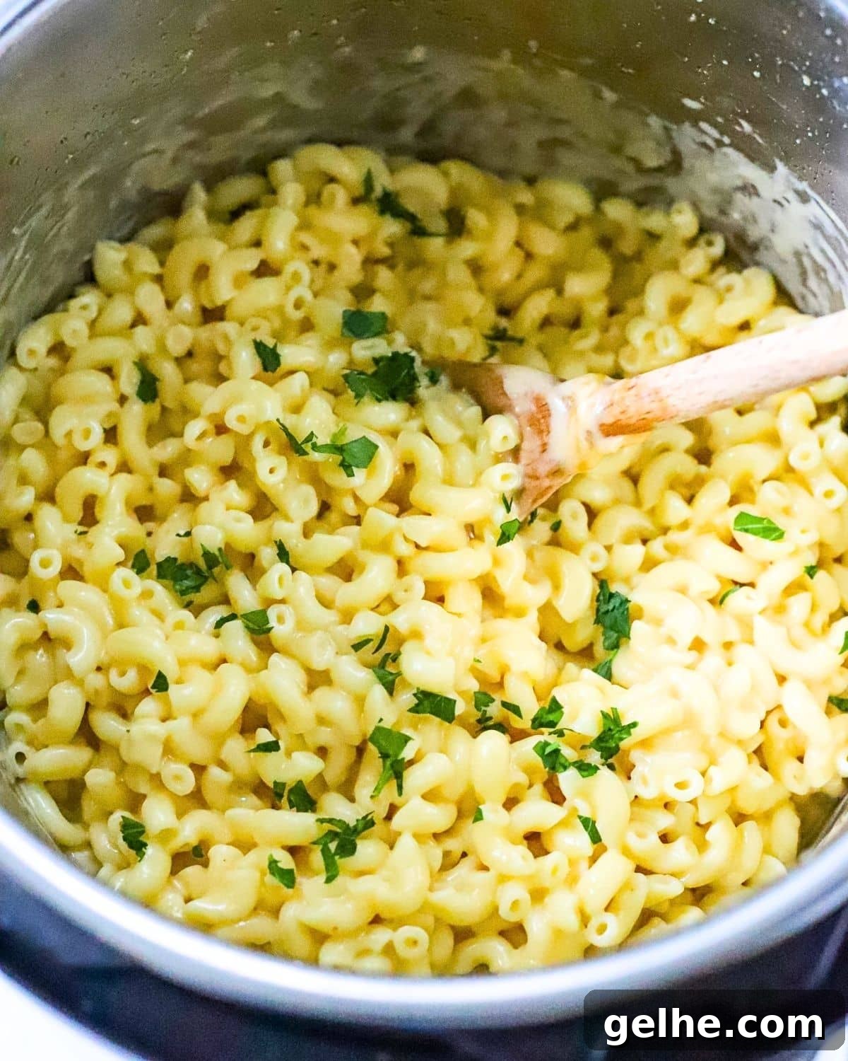 Finished creamy instant pot mac and cheese in the pot with a wooden spoon.