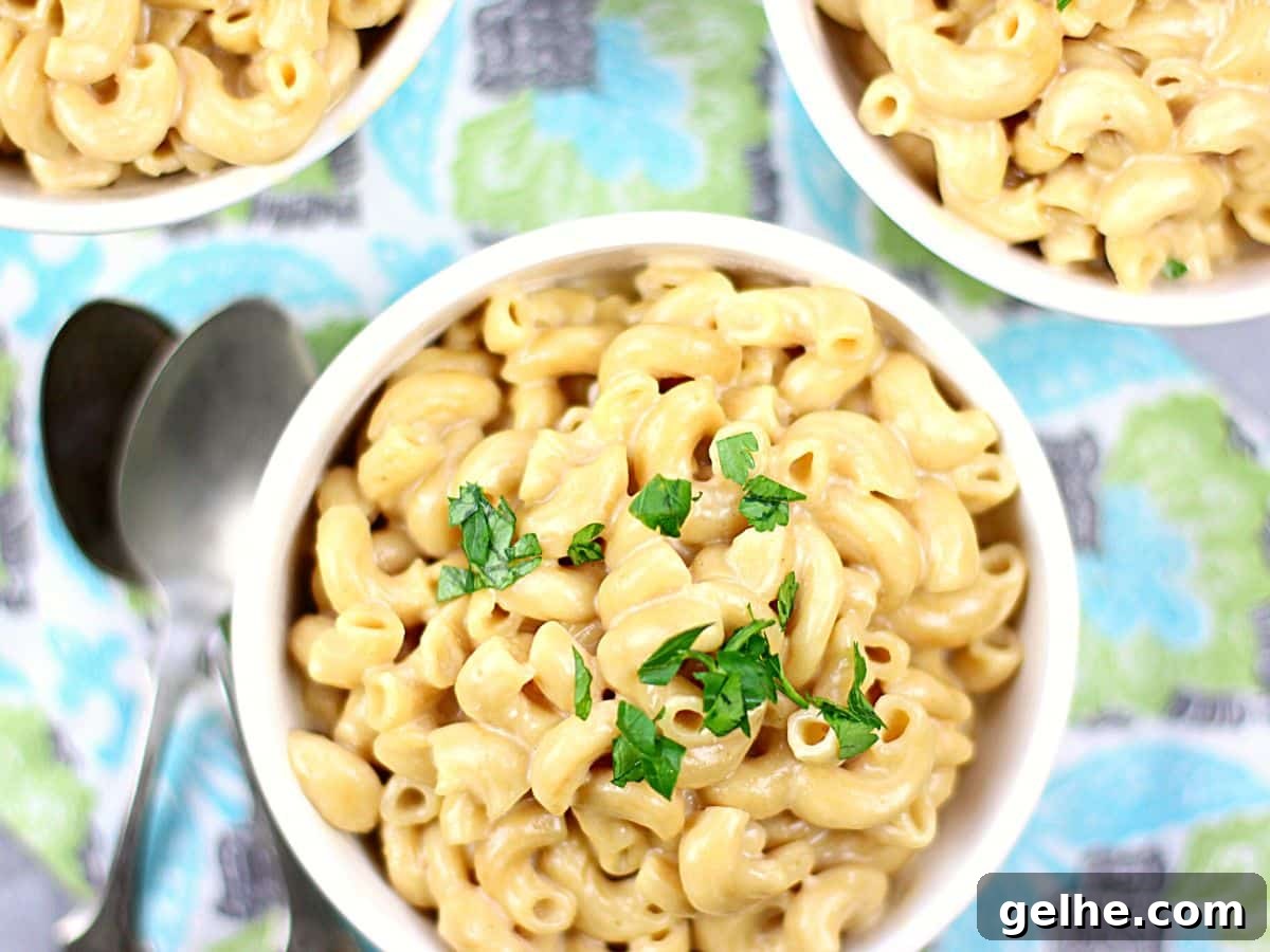 A bowl full of cheesy mac and cheese with parsley on top.
