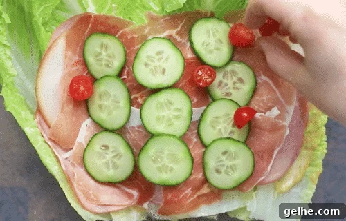 overhead view of lettuce wrap with deli meat, cucumber and cherry tomatoes on a wooden board