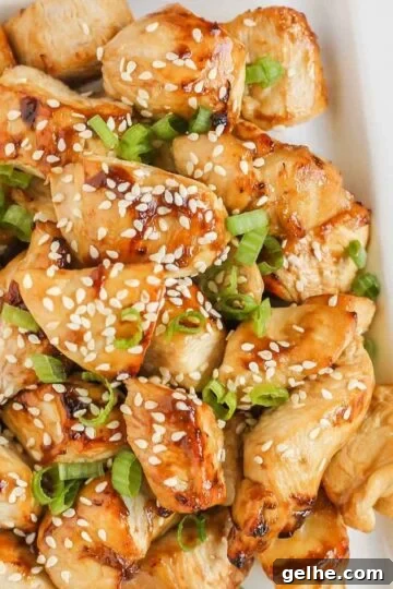Pieces of air fried teriyaki chicken on a white plate.