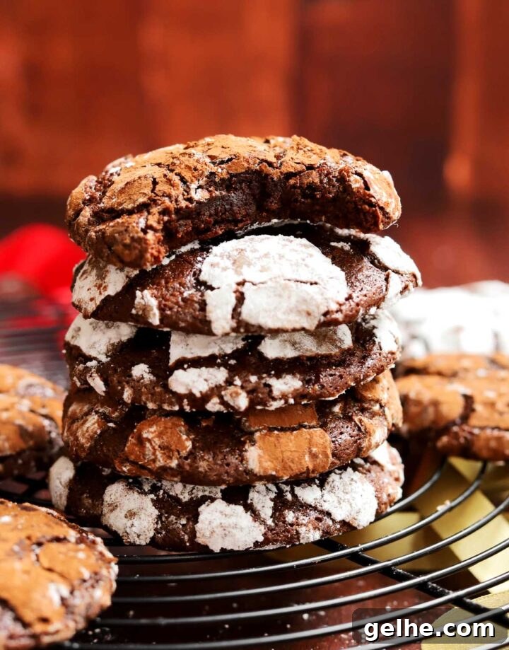 stack of double chocolate crinkle cookies on cooling rack with bite from cocoa crinkle