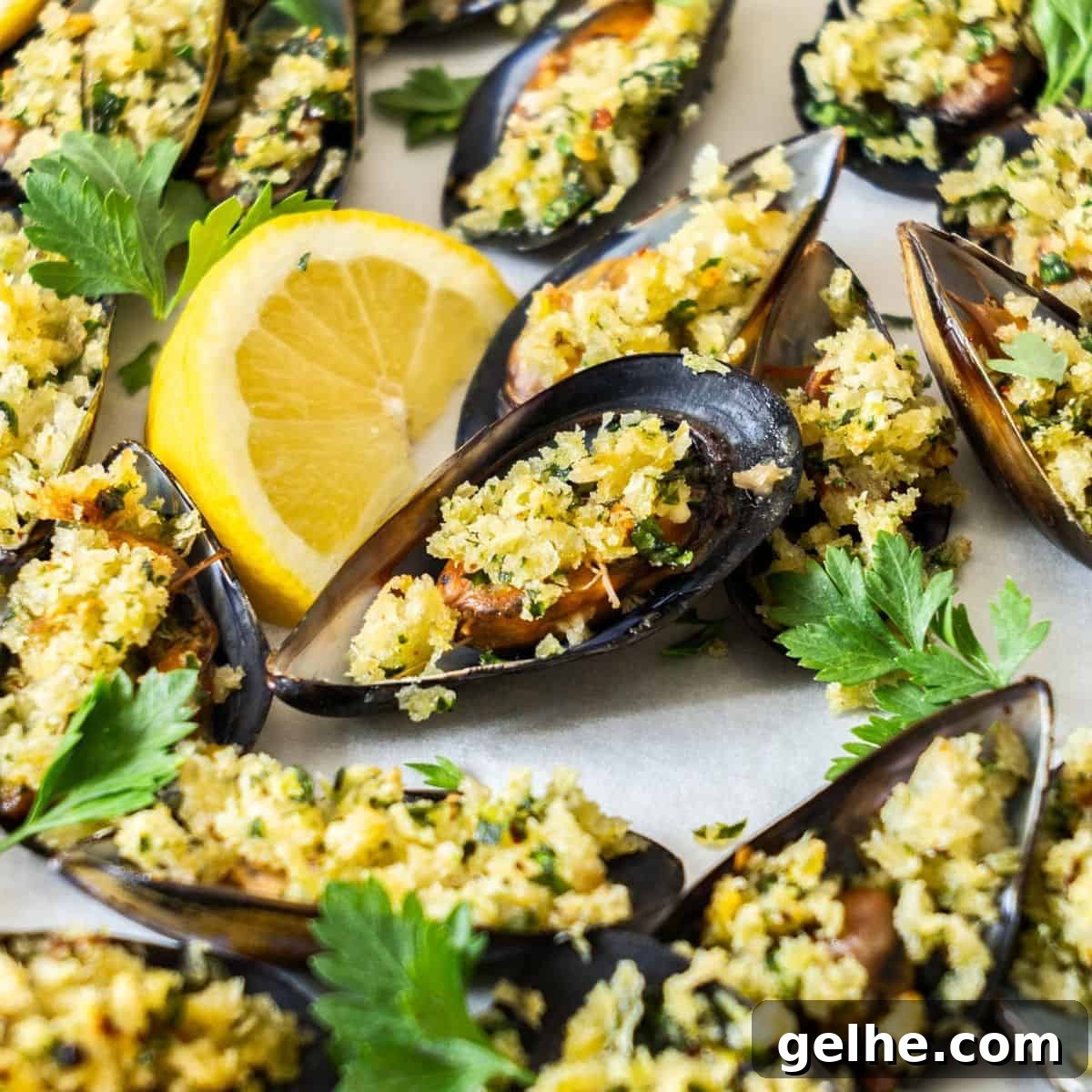 Tray of stuffed Baked Mussels, garnished with some lemon and parsley leaves.