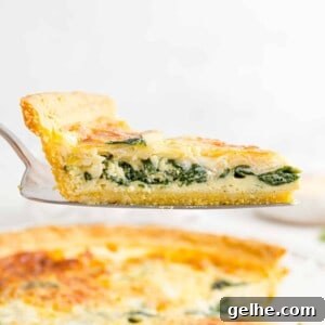 Spinach quiche on a pie server, held above the rest of the quiche.