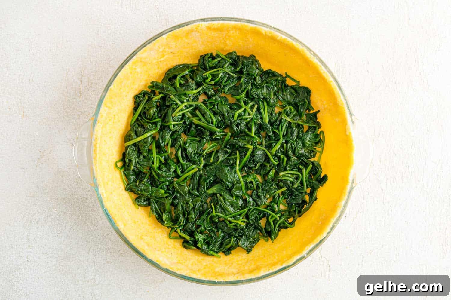 Cooked spinach added to pie crust.