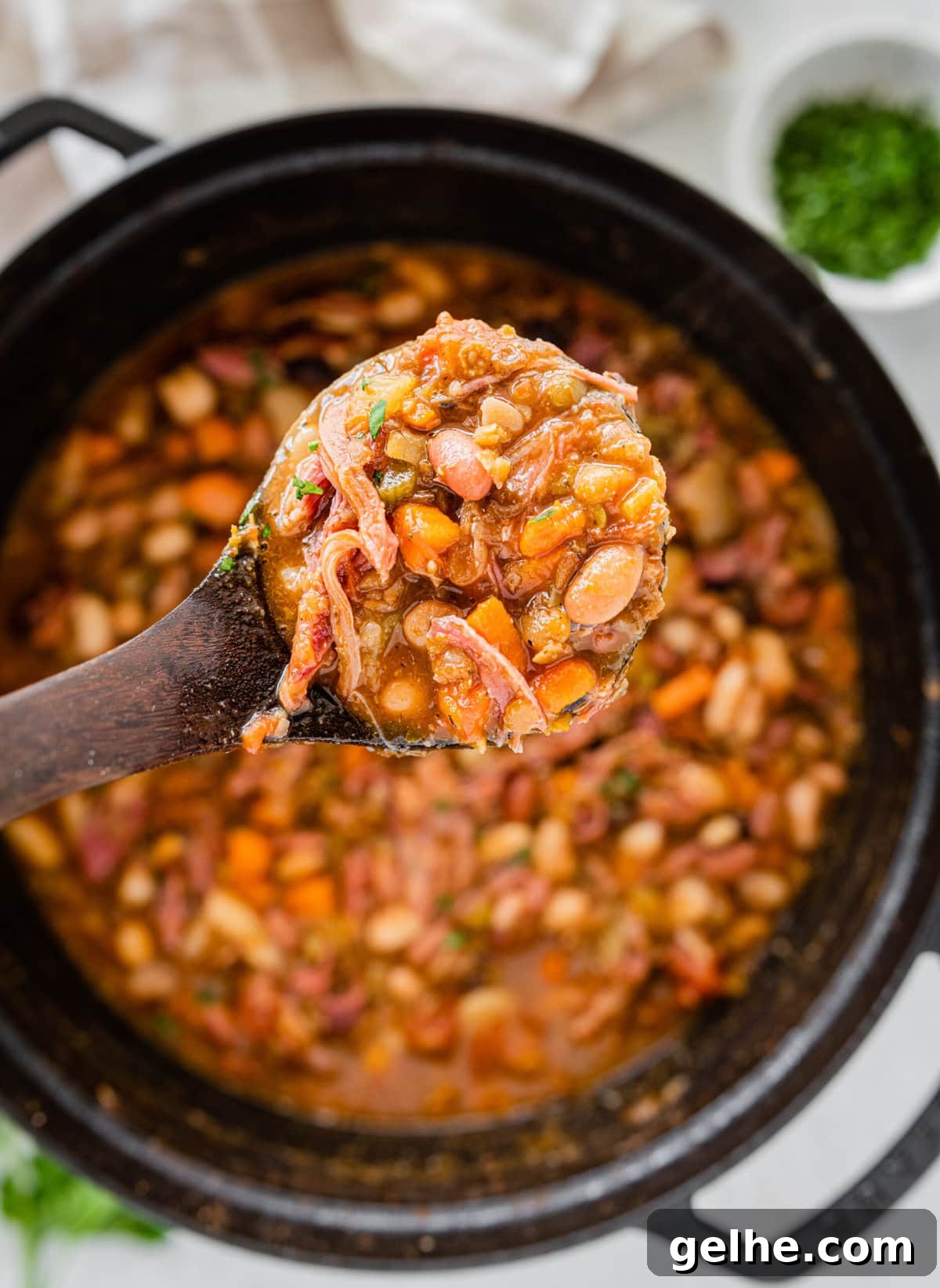 wooden ladle showing the cooked 15 bean soup with ham.