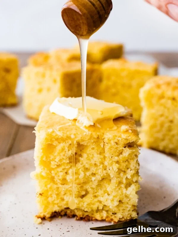 Honey pouring onto a slice of sweet cornbread with butter.
