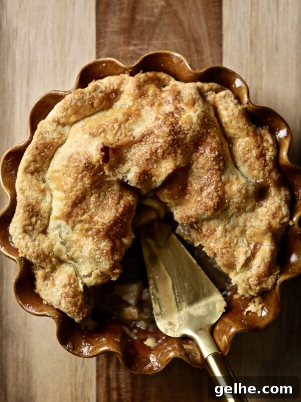 Brown butter apple pie in a brown pie pan missing a slice.