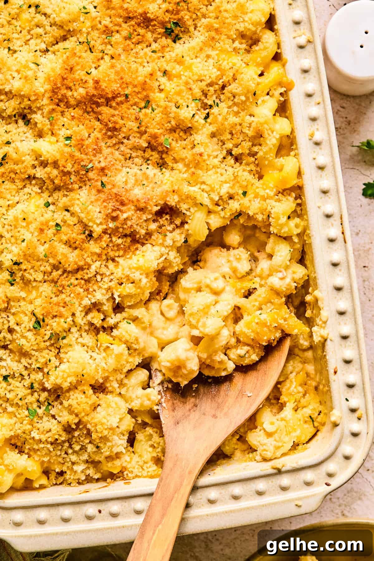 Cheddar gruyere macaroni and cheese in baking pan with spoon scooping into it.