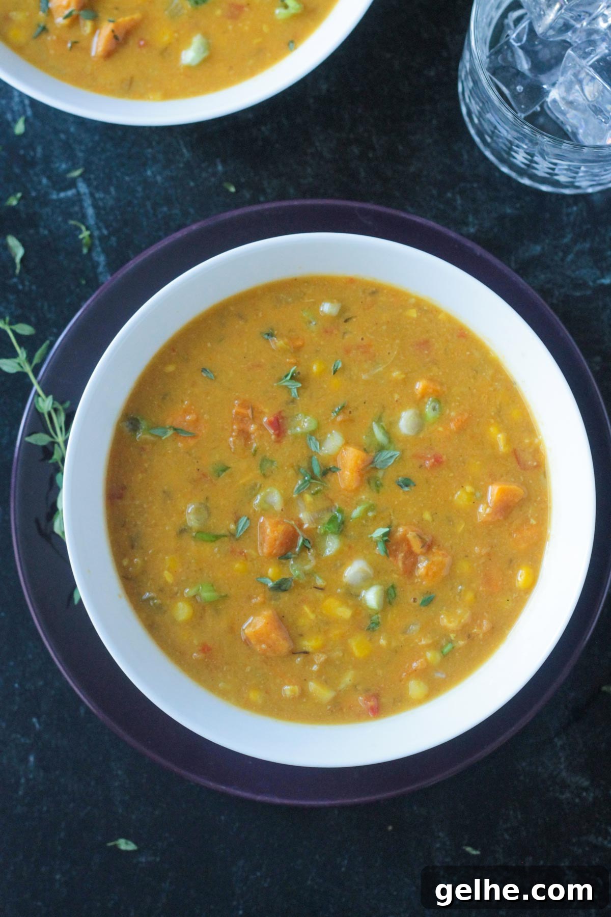 Sweet potato corn chowder in a white bowl garnished with sliced green onions.