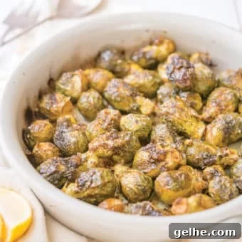 whole roasted brussels sprouts in a round, white ceramic dish on top of a linen towel