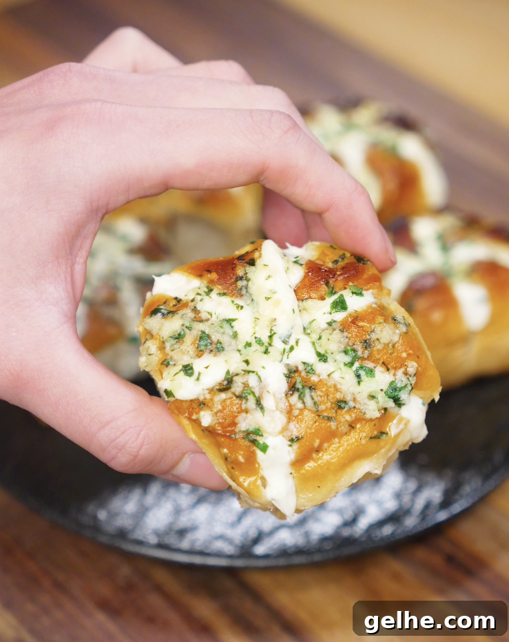 Korean Garlic Cheese Bread Recipe — Crispy, Cheesy Garlic Pull-Apart 3 A hand holds up a finished Korean Garlic Cheese Bread roll, showing the golden top, cheesy filling, and parsley garlic glaze.