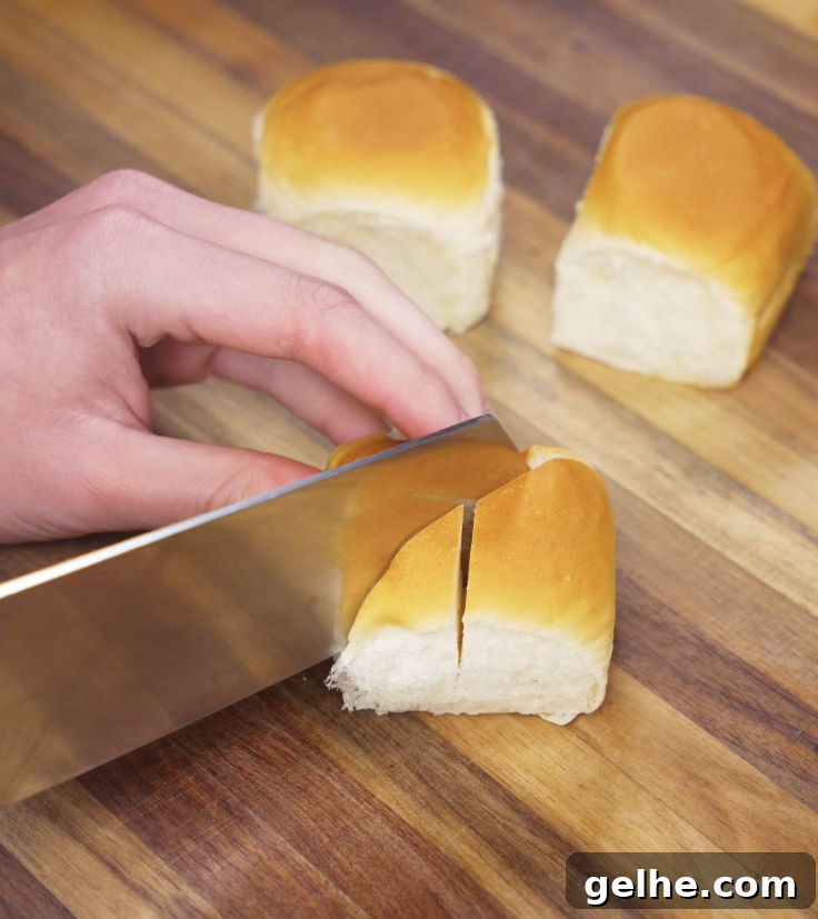 Korean Garlic Cheese Bread Recipe — Crispy, Cheesy Garlic Pull-Apart 6 A hand carefully cuts deep slits into a soft bread roll on a wooden cutting board, prepping it for filling.